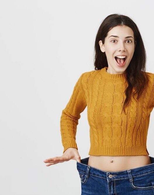 Woman showing loose jeans and weight loss