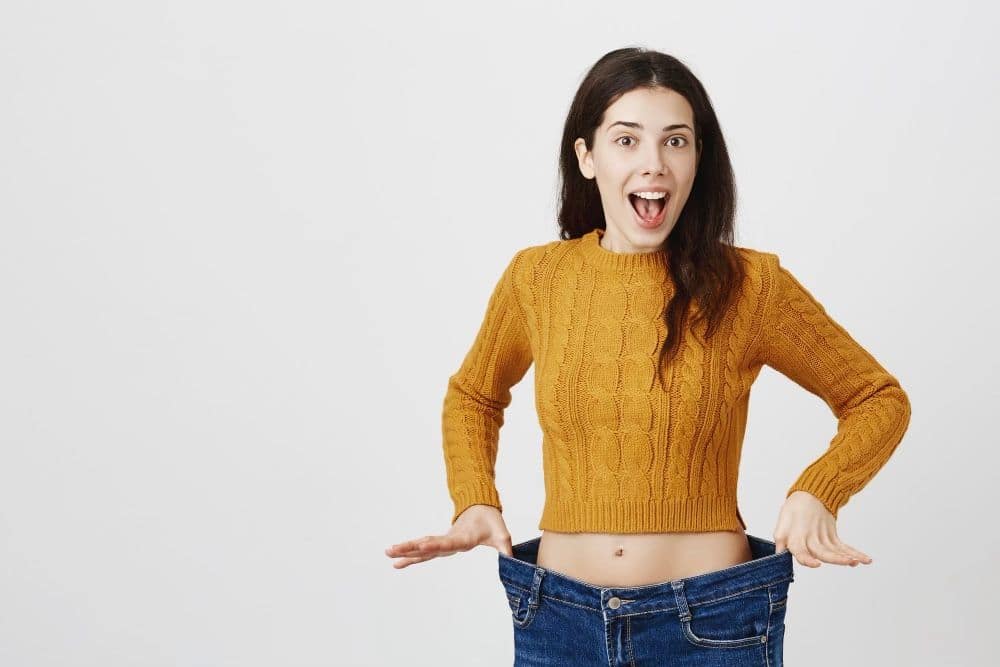 Woman showing loose jeans and weight loss