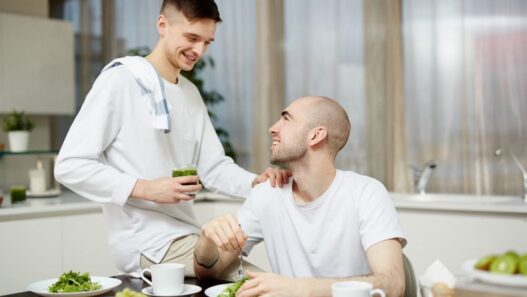 2 men in kitchen, one eating green veg and other serving, Bone marrow transplant recovery, cancer nutrition