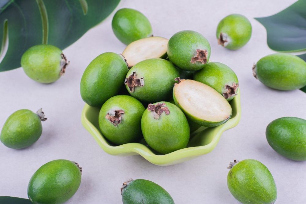 Green coloured Monk fruit in bowl and on floor