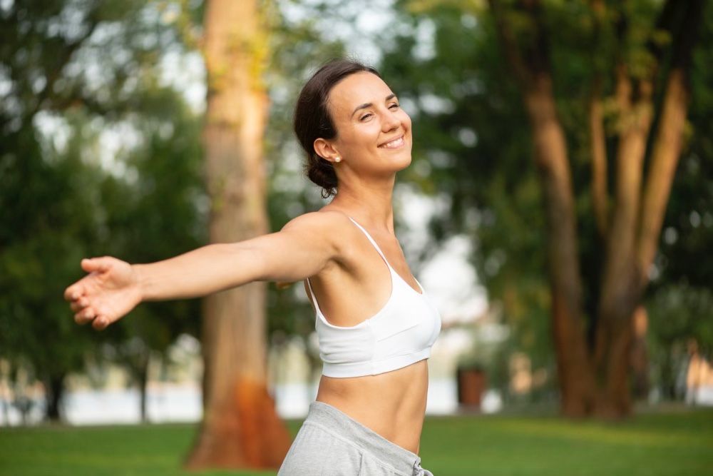 Woman in park raising arms, what does a healthy person look like