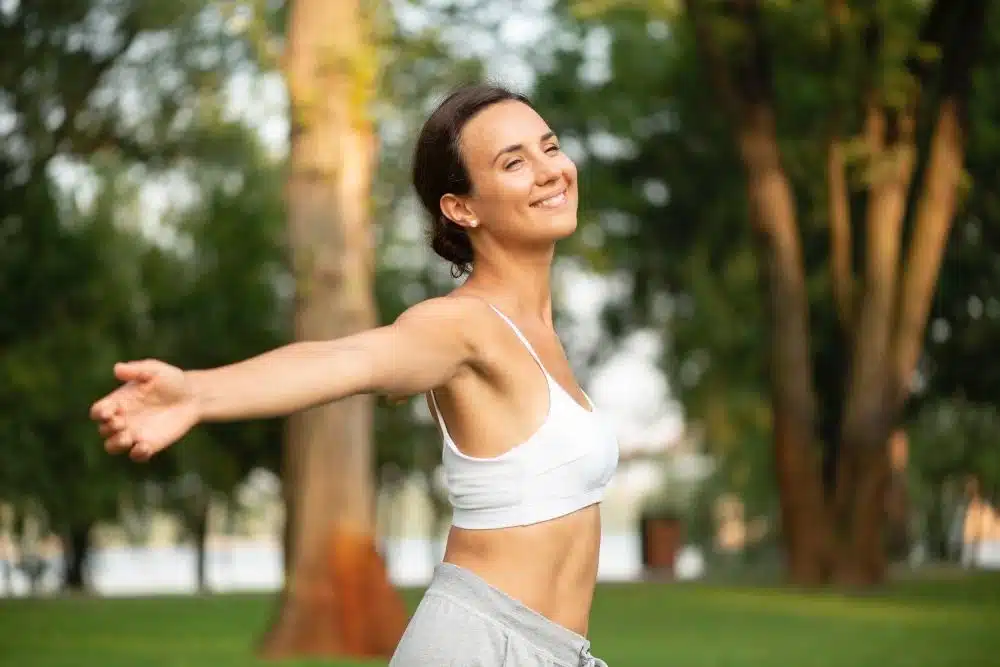 Woman in park raising arms, what does a healthy person look like