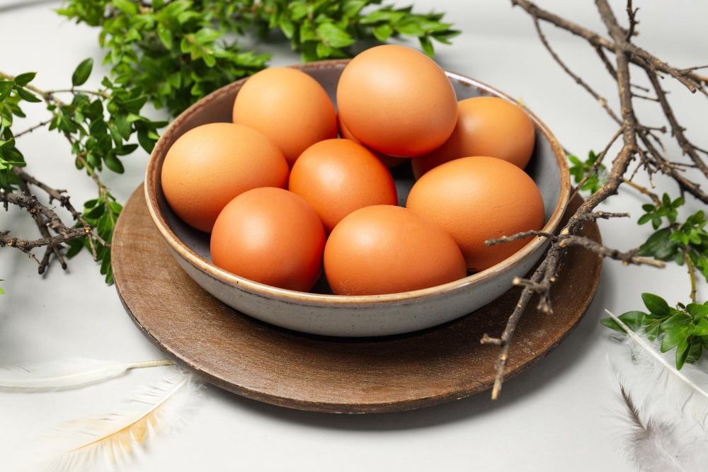 Omega 3 eggs in a bowl surrounded by green leaves