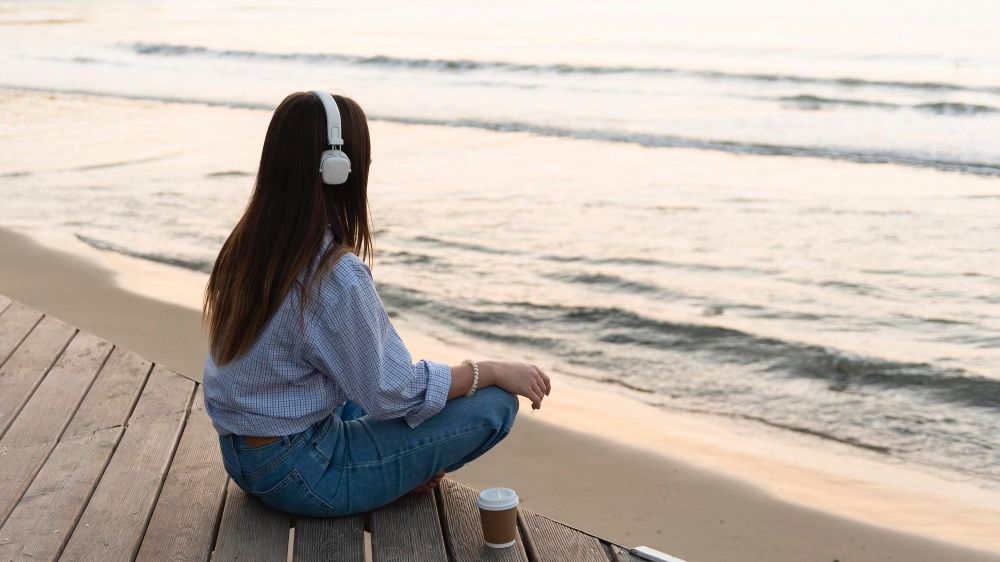 Woman listening to music at the beach as diversionary activities