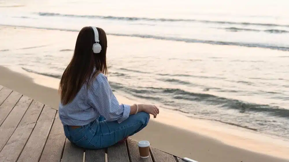 Woman listening to music at the beach as diversionary activities