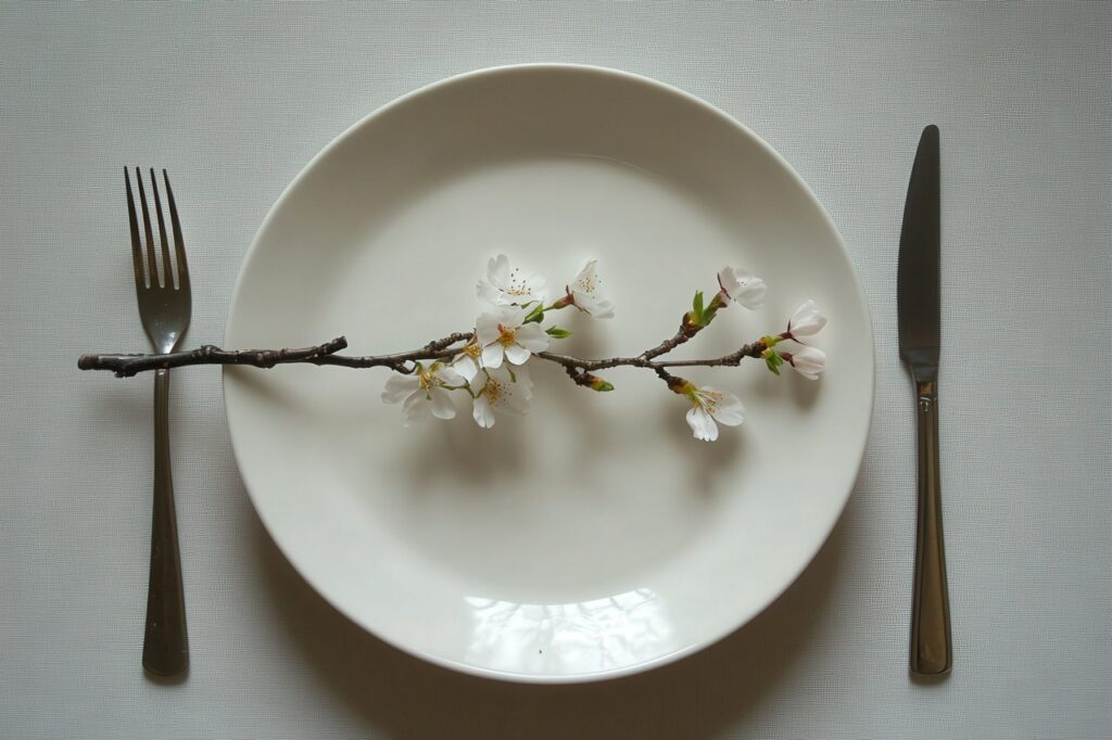 5:2 fasting, intermittent fasting health benefits, types, A minimalist spring table setting with a white plate, silver cut