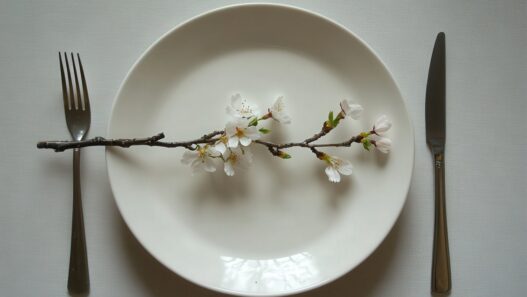 5:2 fasting, intermittent fasting health benefits, types, A minimalist spring table setting with a white plate, silver cut