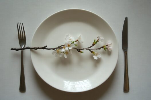 5:2 fasting, intermittent fasting health benefits, types, A minimalist spring table setting with a white plate, silver cut