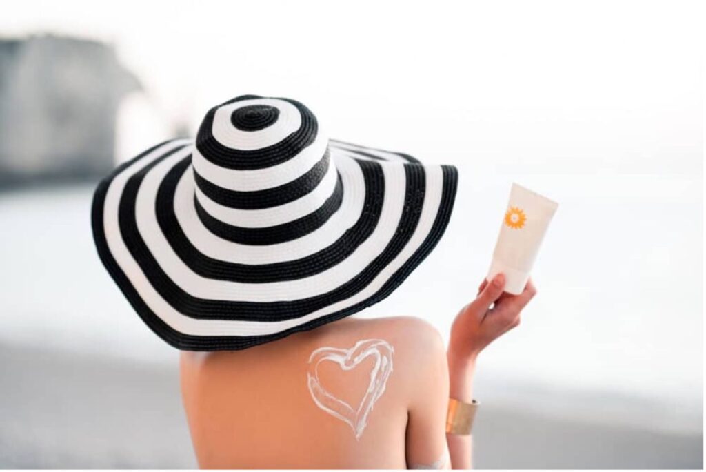 Woman back wearing hat and sunscreen SPF 30 vs 50, physical vs chemical sunscreen, how to choose the best sunscreen