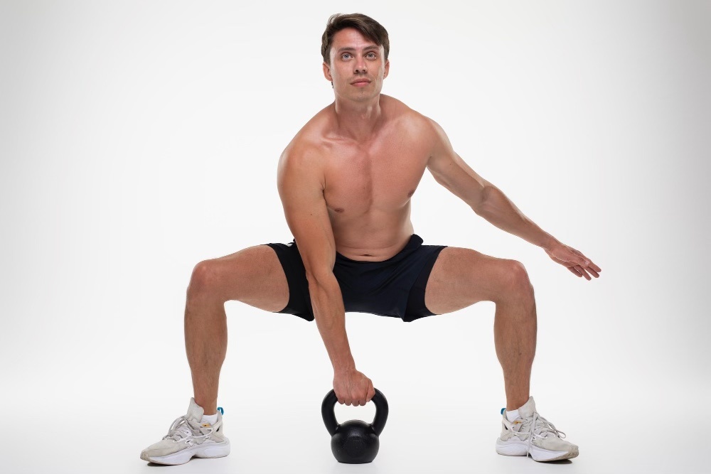 Man with kettlebell doing squats for peak performance training