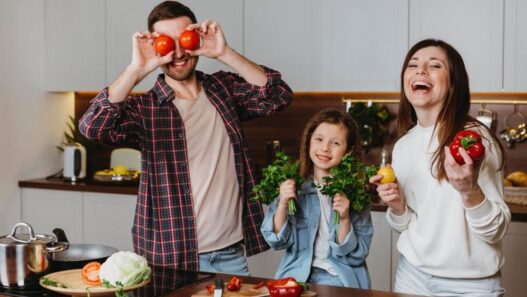 man, woman, child in kitchen showing healthy fruits and vegetables