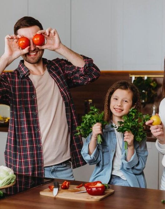 man, woman, child in kitchen showing healthy fruits and vegetables