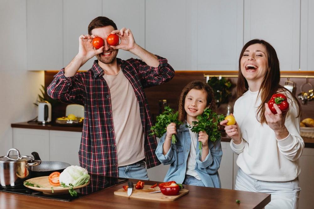 man, woman, child in kitchen showing healthy fruits and vegetables