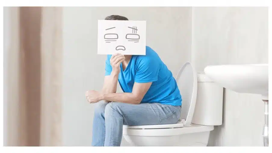 Child sitting in toilet seat holding sad face drawing on paper due to chronic idiopathic constipation