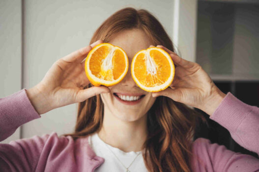 woman showing nutrition two oranges close to her eyes for nutrition and eye health