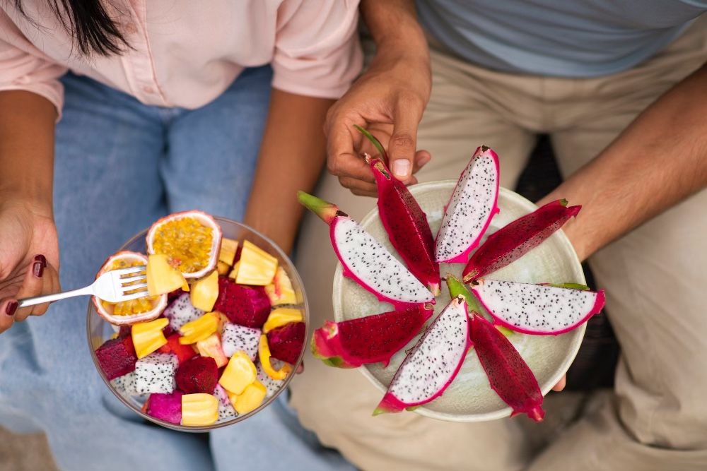Man and woman eating salad of yellow dragon fruit, yellow pitaya