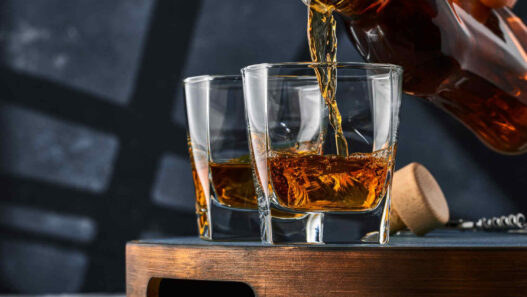 bottle pouring whiskey in two glasses