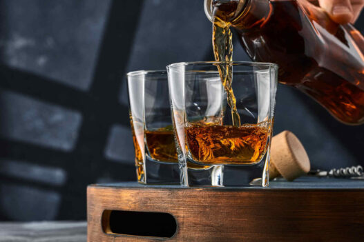 bottle pouring whiskey in two glasses