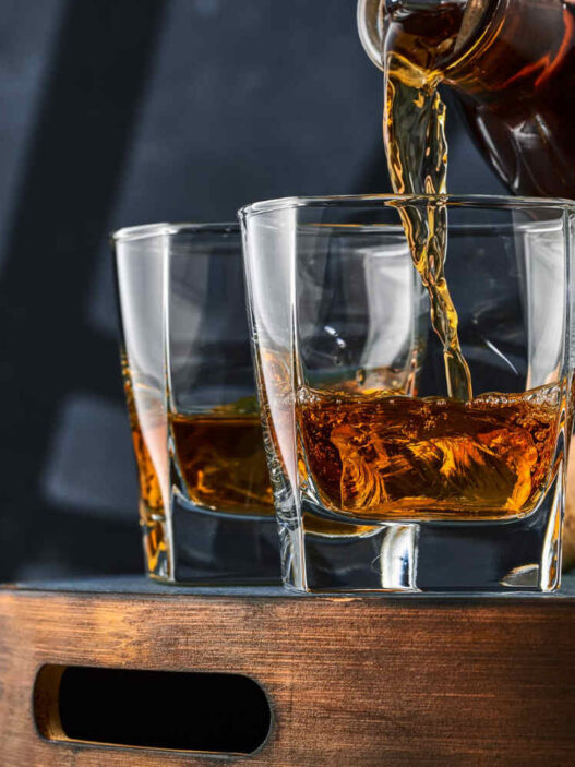 bottle pouring whiskey in two glasses