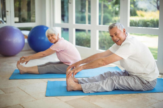 two senior man and woman doing gentle yoga