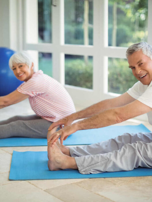 two senior man and woman doing gentle yoga