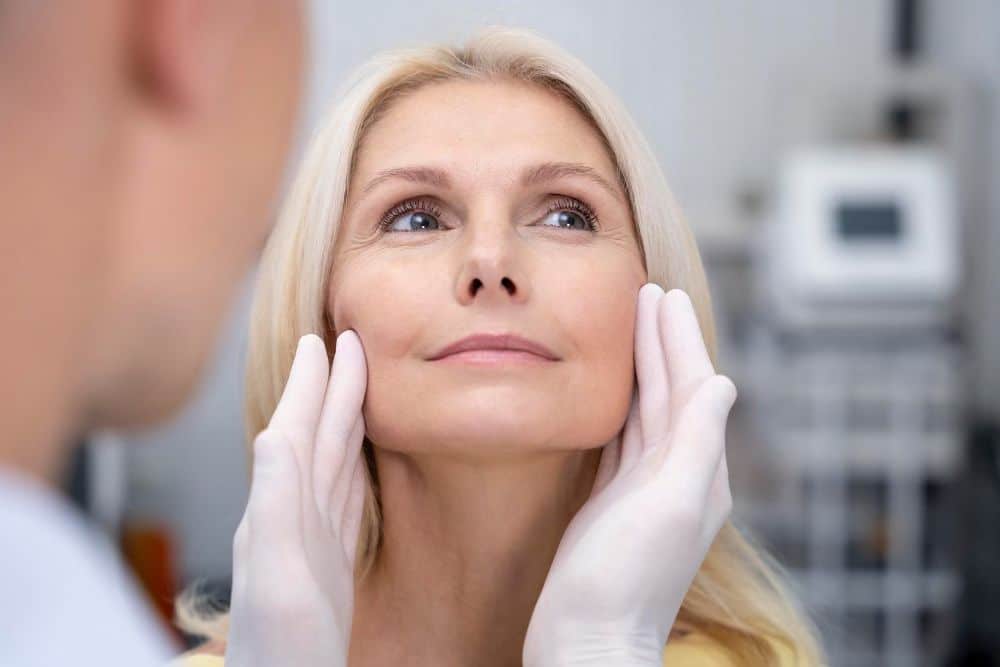 Doctor examining woman for facelift surgery or rhytidectomy