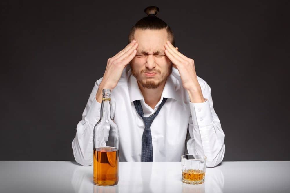 Man having headache after Xanax and Alcohol, Whiskey bottle and glass