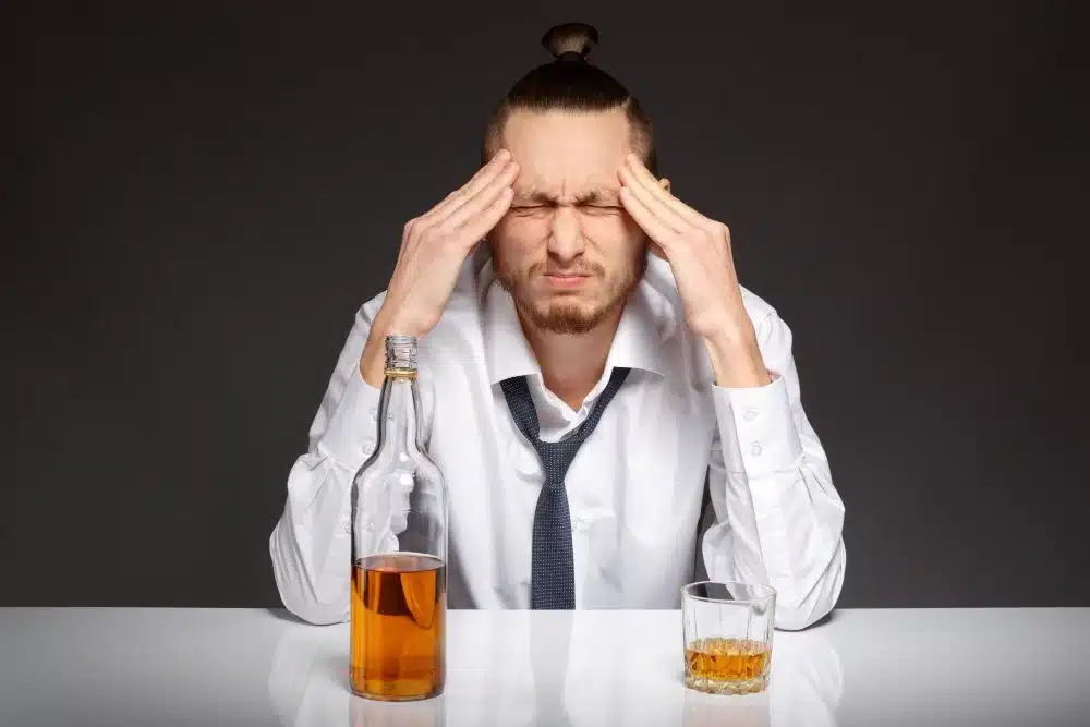 Man having headache after Xanax and Alcohol, Whiskey bottle and glass
