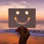 hand with smiley face on paper during sunset, optimism