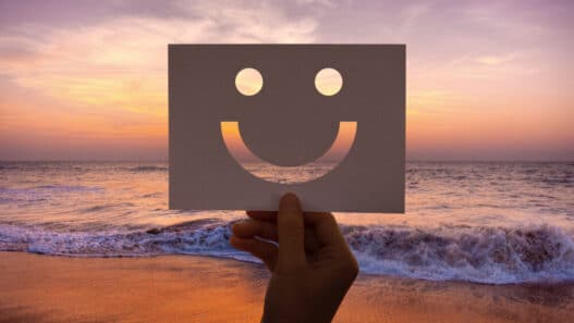 hand with smiley face on paper during sunset, optimism