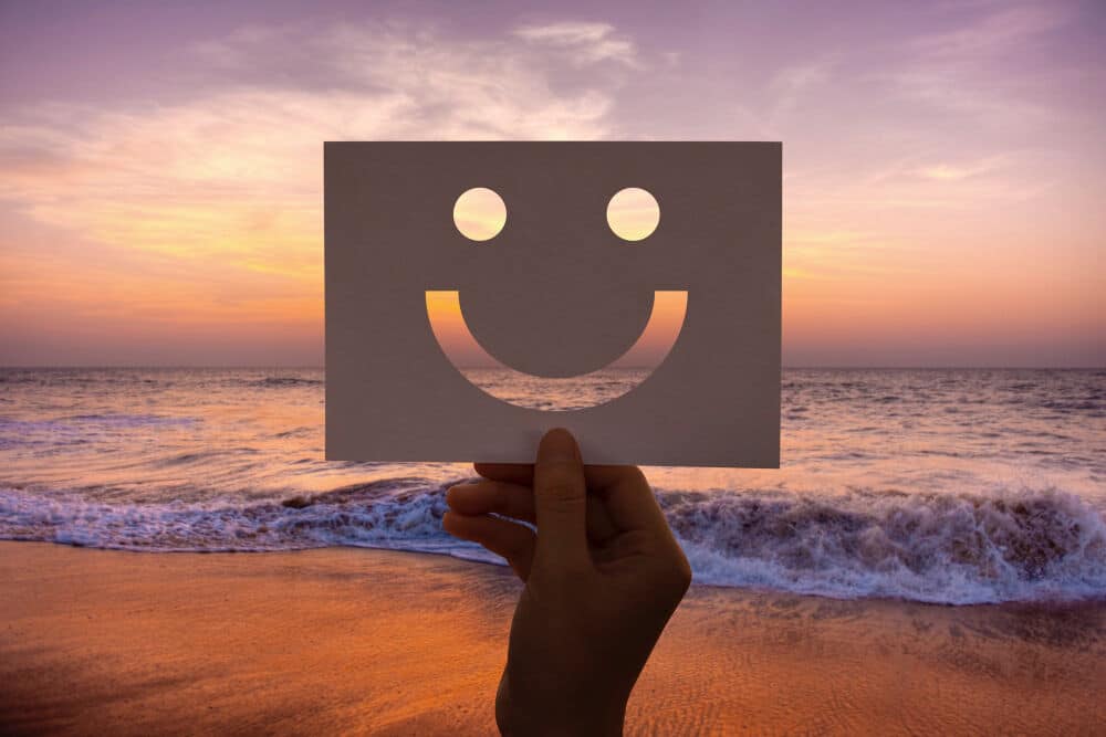 hand with smiley face on paper during sunset, optimism