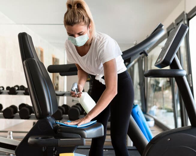 Woman cleaning the cycle in gym